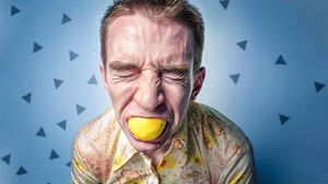 Mann beißt in saure Zitrone